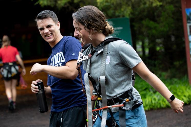 Two students laugh together at the ropes course.