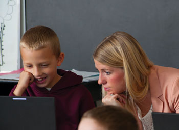 Lauren Porter ’14 works with second-graders at Eureka Elementary School. The students were researching animal life cycles on laptops and creating PowerPoint presentations to share with the class