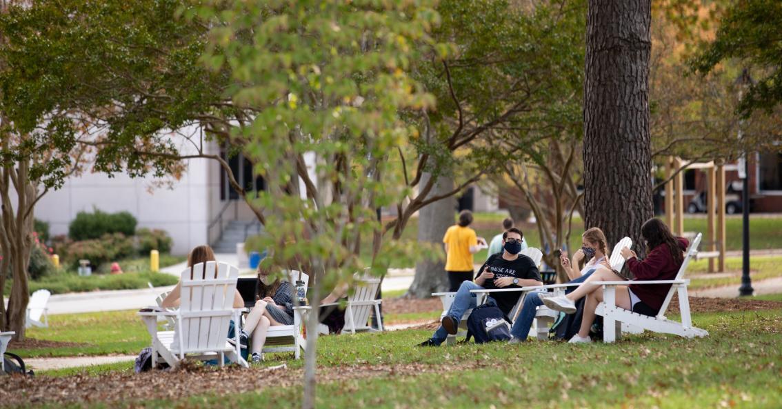 Students sitting on Stubbs Mall in Adirondack chairs