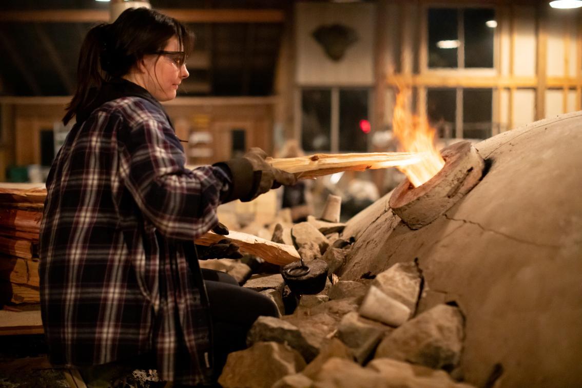 Person tends to the fire in the kiln