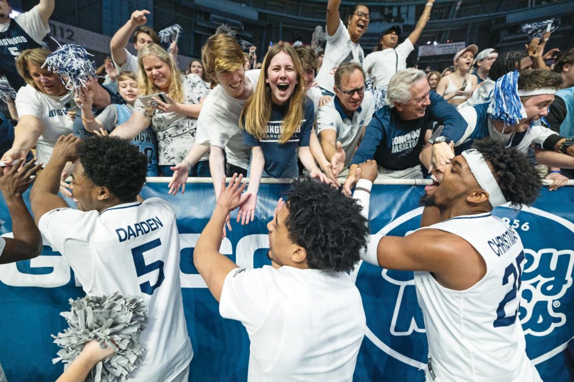 Basketball players greet fans after a game