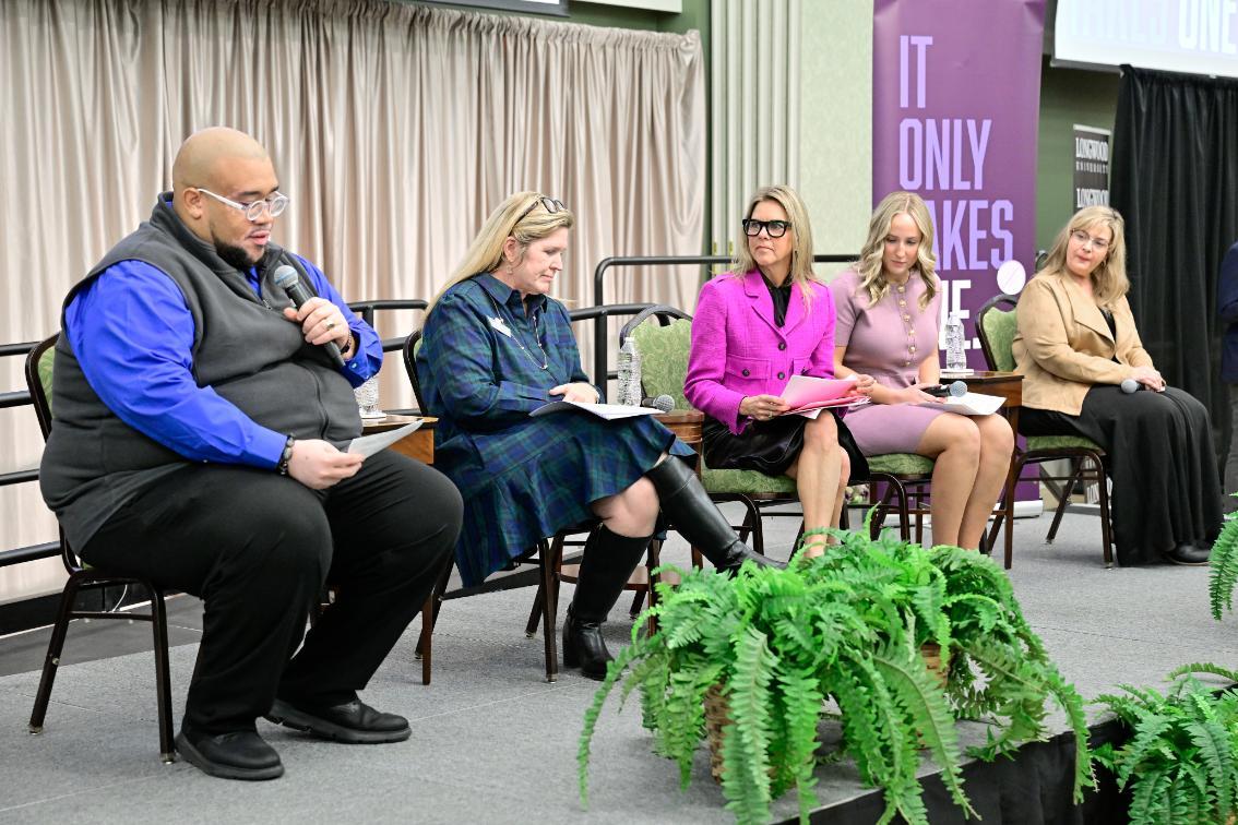 Cam Patterson, VP for Student Affairs, speaks into a microphone, accompanied on stage by other campus officials and former First Lady Youngkin
