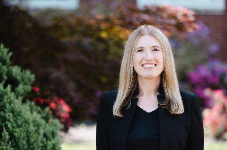 Headshot of Dr. Tai Johnson, assistant professor of history, standing in front of the colorful, flowering bushes that adorn the front of Eason Hall.